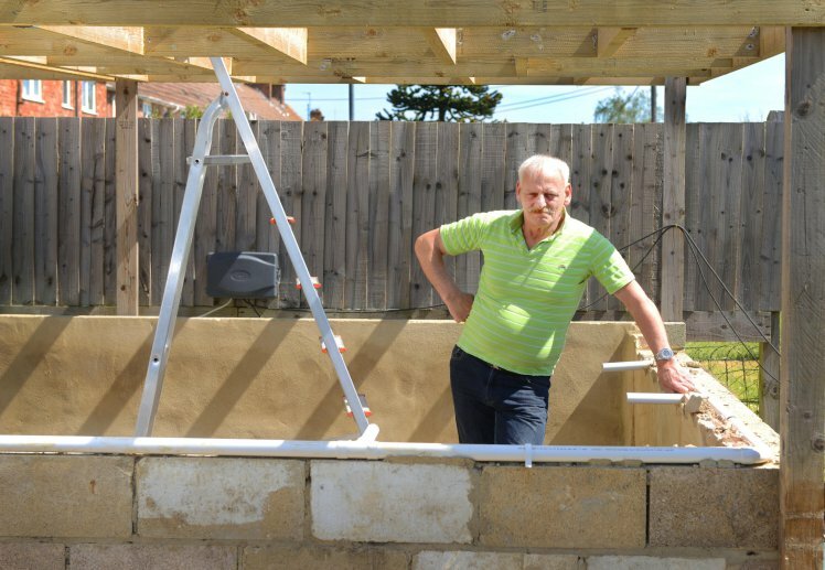 Kevin Sheehan with his homemade pond which he has been told to remove. See SWNS story SWPOND; A man has been ordered to remove a fish pond from his back garden over fears it could be dangerous - 'for BURGLARS'. Kevin Sheehan, 62, claims he was told the pond posed a ìpossible riskî to members of the public because itís not clearly visible from the other side of his garden fence. The structure, which is home to 80 fish, has a wall of concrete blocks surrounding it and the entire garden is surrounded by a 6ft wooden fence. Kevin claims his landlords, Sovereign, started complaining when he added two extra concrete blocks around the water's edge to stop his one-year-old daughter, Olivia, falling in.